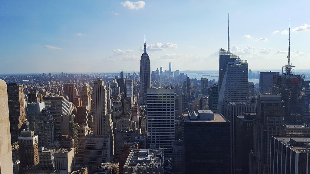 View looking south from a top-floor building in Manhattan, with the skyline, including the Empire State Building, in the distance.