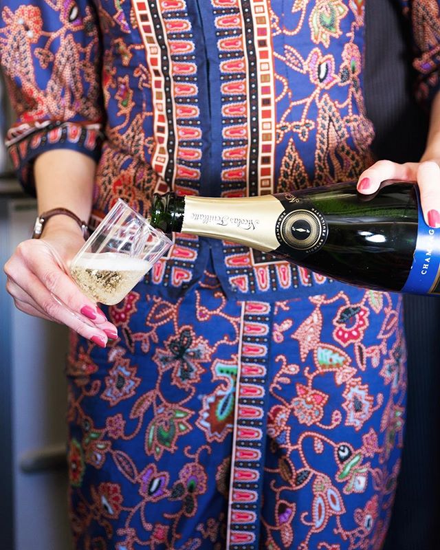 This is a photo of a Singapore Air flight attendant pouring a glass of champagne into a cup.