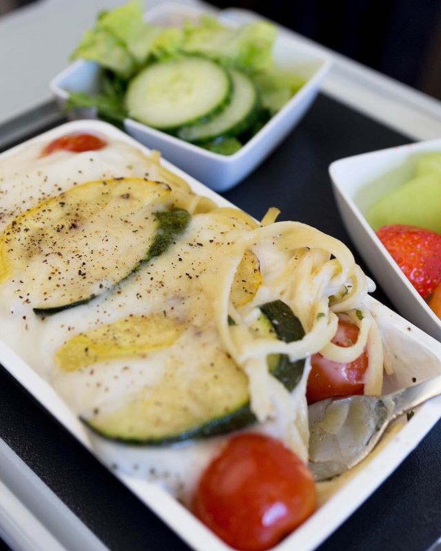 This is a photo of a zucchini salad with roma tomatoes on a small plate aboard a Singapore Air flight.