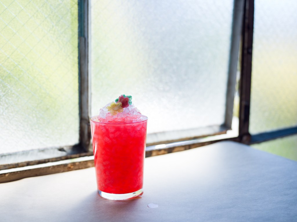 This is a photo of a pink iced drink with a red fruit on top.