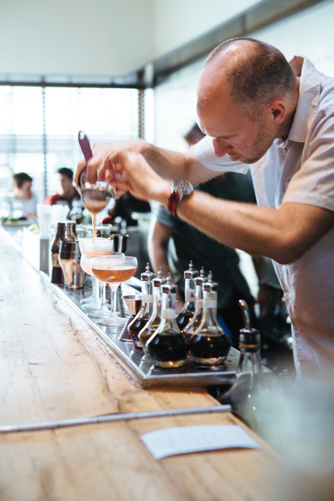 This is a photo of a bar tender mixing a cocktail at a bar.