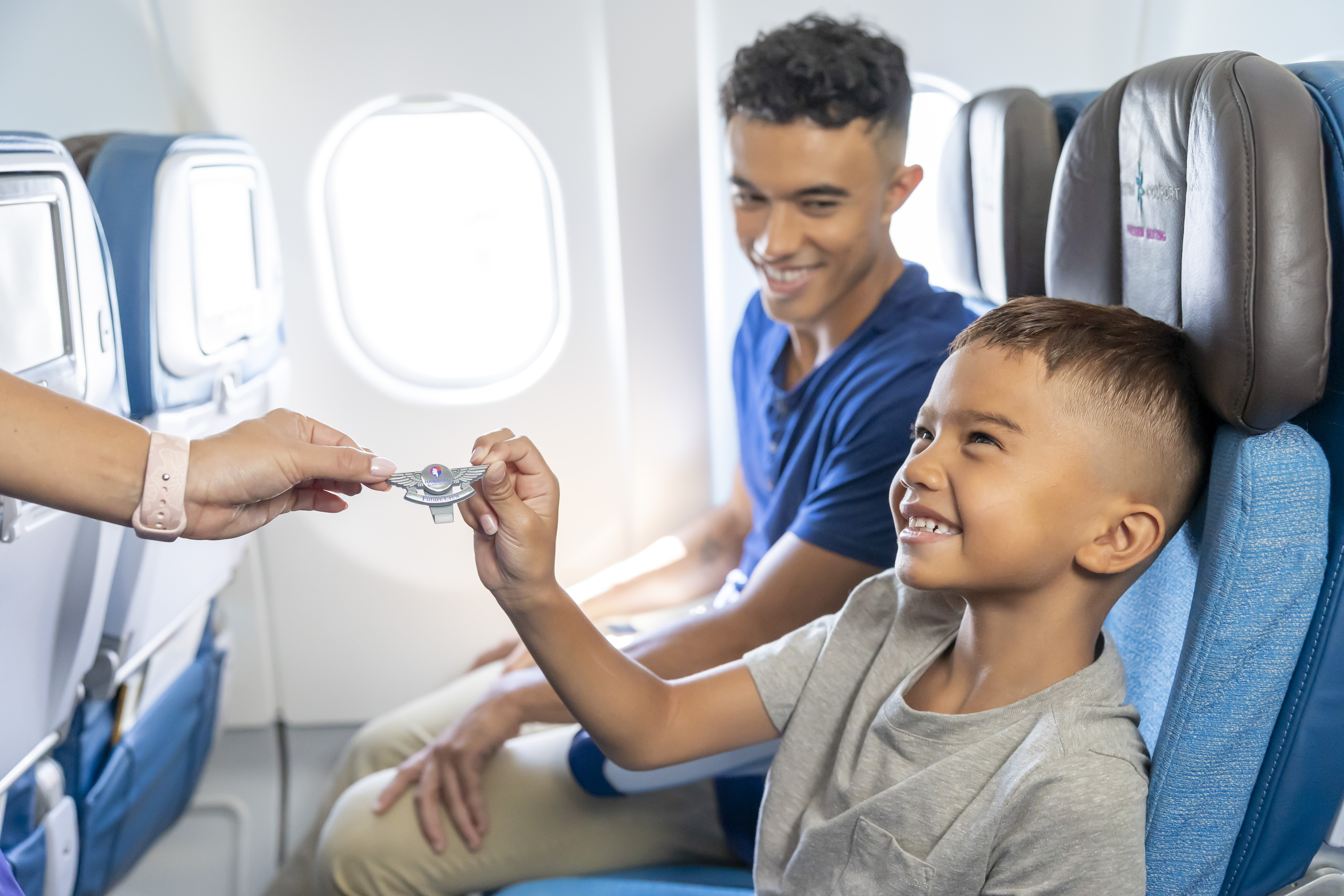A child accepting Hawaiian Airlines Keiki Wings from a flight attendant
