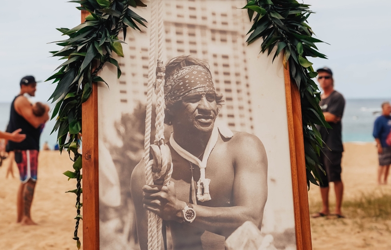 A photo of Eddie Aikau draped in lei at the opening ceremony. Eddie_Opening_Ceremony_120519-15