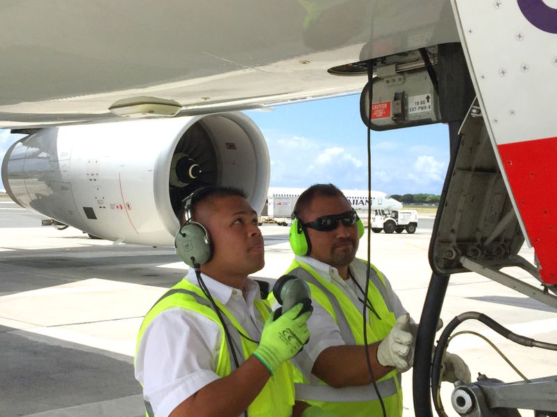 Hawaiian Airlines ground crews connect external power to a wide-body aircraft at Honolulu International Airport. HA APU Initiative 1