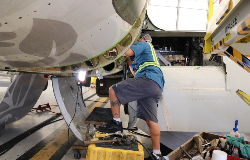 One of our mechanics repairing a piece of sheet metal on the lower portion of a fuselage. IMG_3474