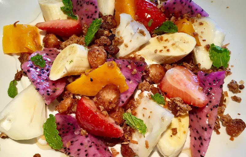 Kokohead Cafe's local fruit and granola plate, made with poi yogurt, pink dragonfruit, white pineapple, Makaha mango, apple banana, Kula strawberries, house-made coconut-candies, mac nut yogurt, Christmas berry honey, mint, and lime zest. LW4